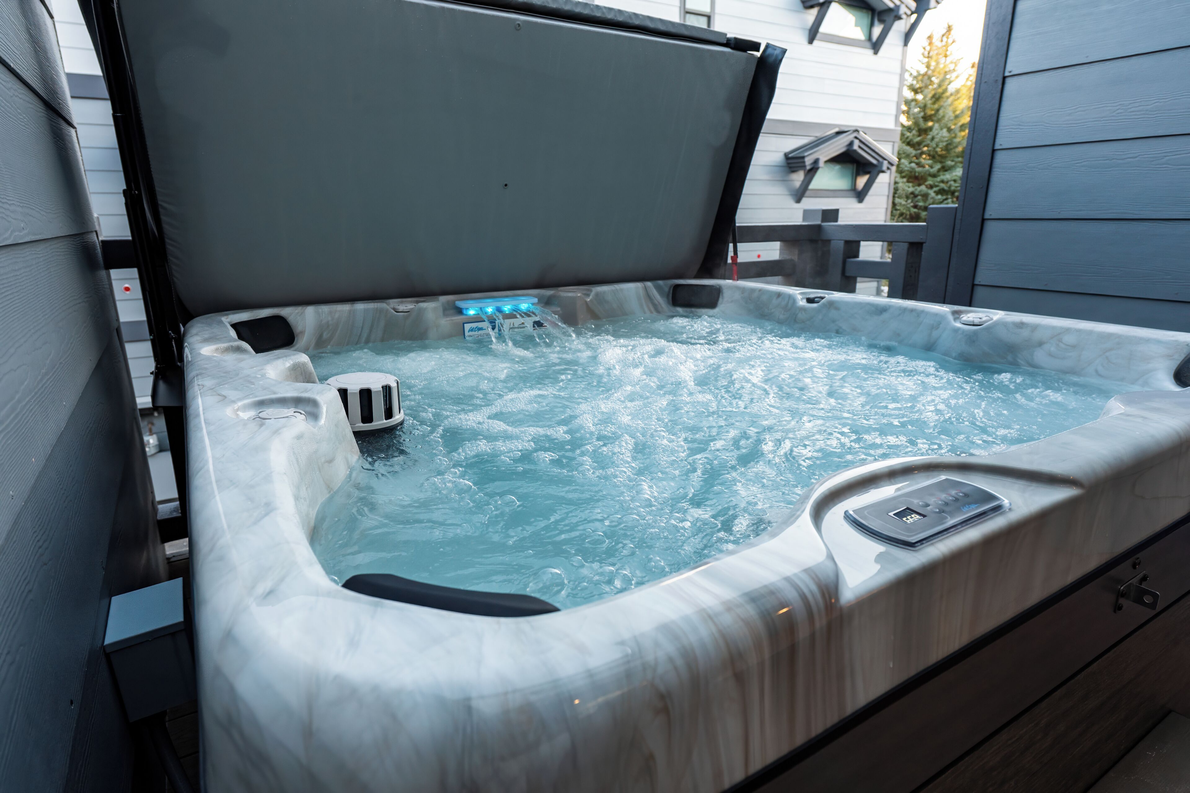 A hot tub with a control panel, water jets, and a cover.
