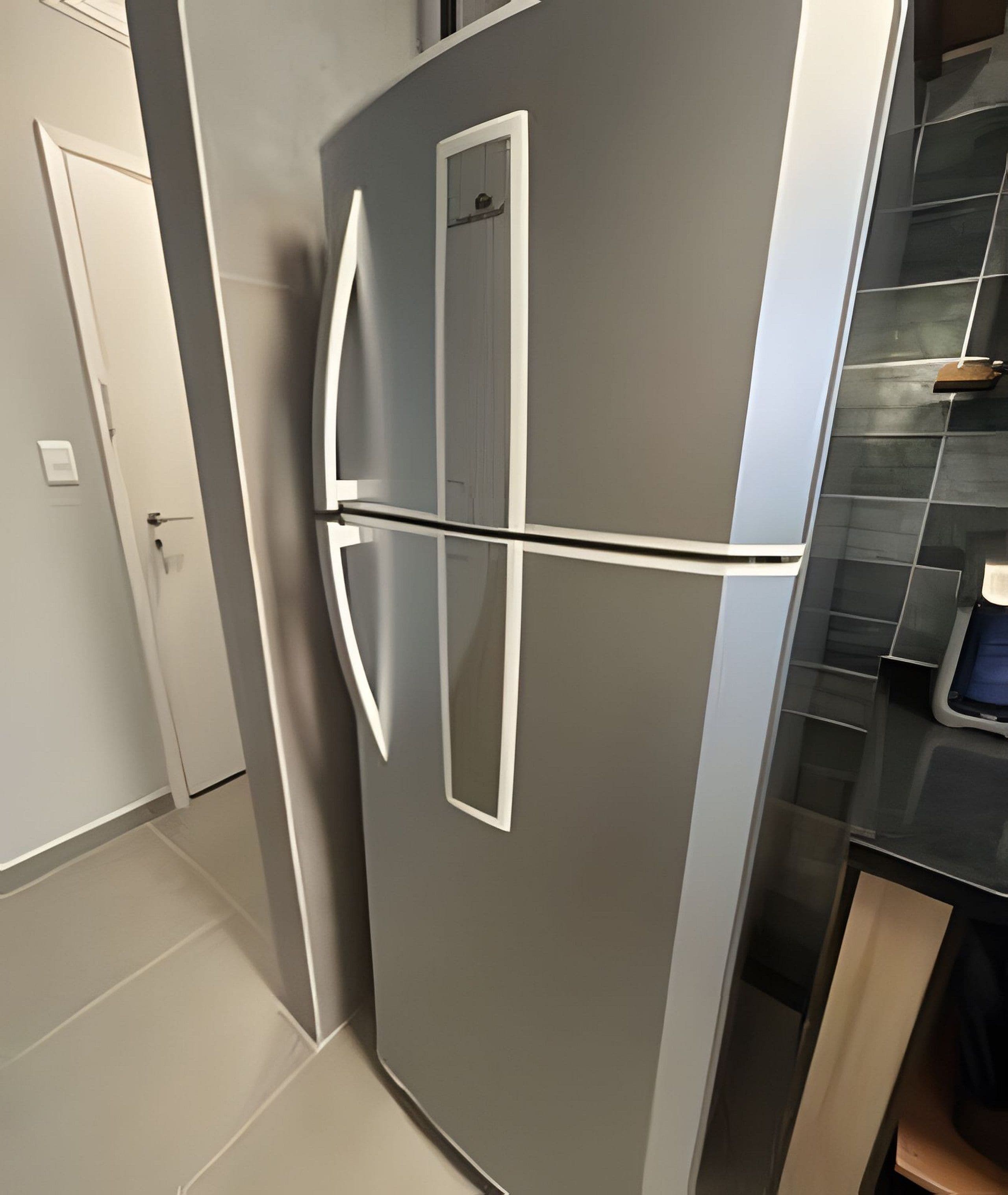 Een moderne keuken met een roestvrijstalen koelkast, een witte deur en een betegelde spatwand.