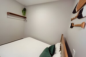 A bedroom with a bed, a wooden headboard, a shelf with a plant, and a wall-mounted wooden object.