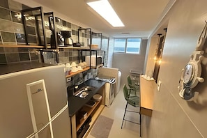 A compact kitchen with a built-in oven, a sink, and a dining area with a chair. - SHB - O Melhor de Pitangueiras  (Guarujá)