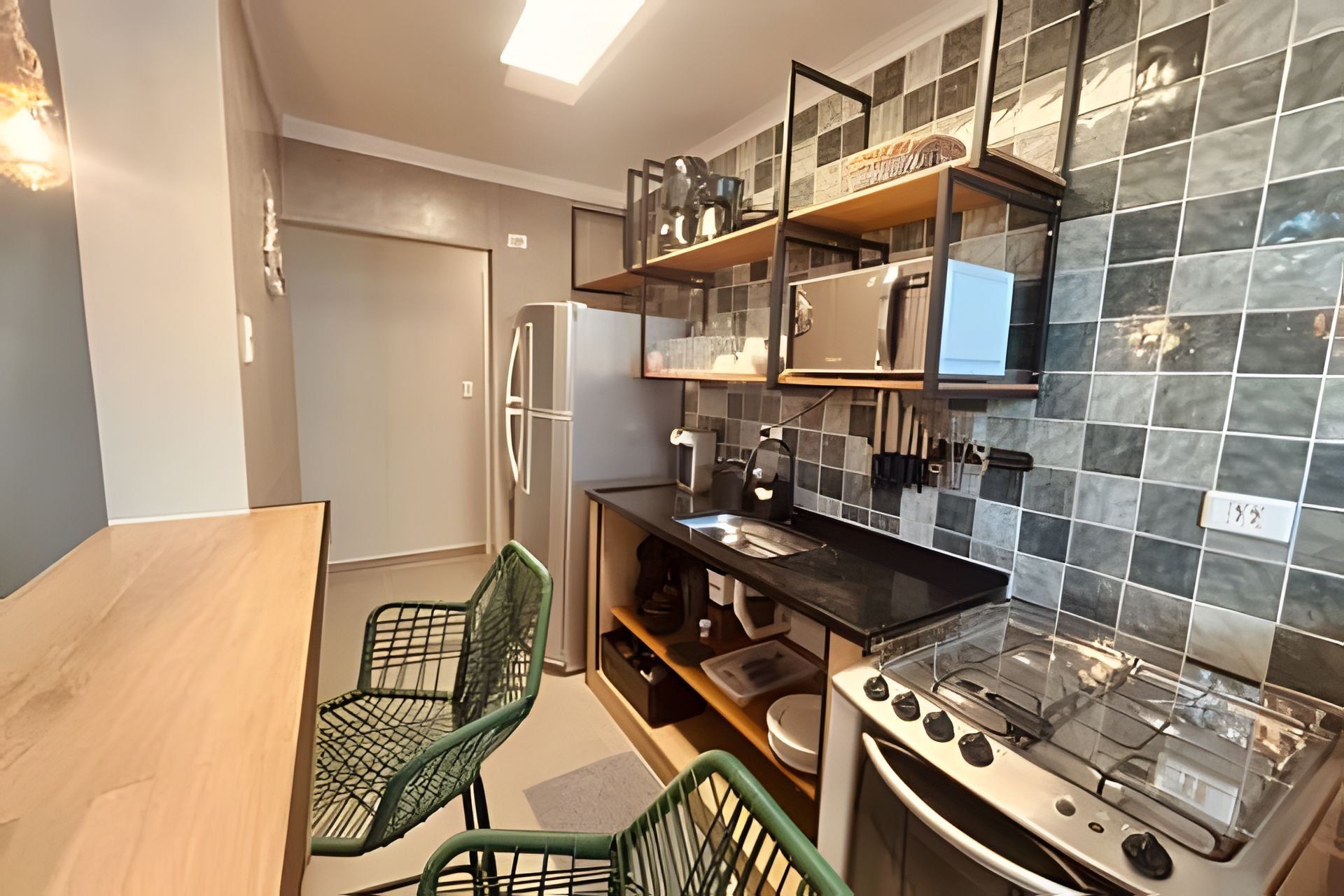 Een praktische keuken met een koelkast, fornuis en een kleine eethoek met stoelen.