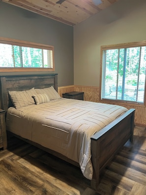 A bedroom with a wooden bed, two nightstands, and a window with blinds. - Bikers retreat (Deerwood)