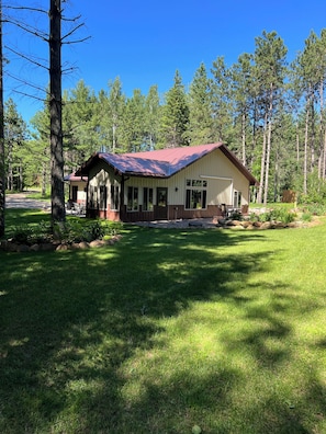 A lodge with a red roof, a porch, and a well-maintained lawn. - Bikers retreat (Deerwood)