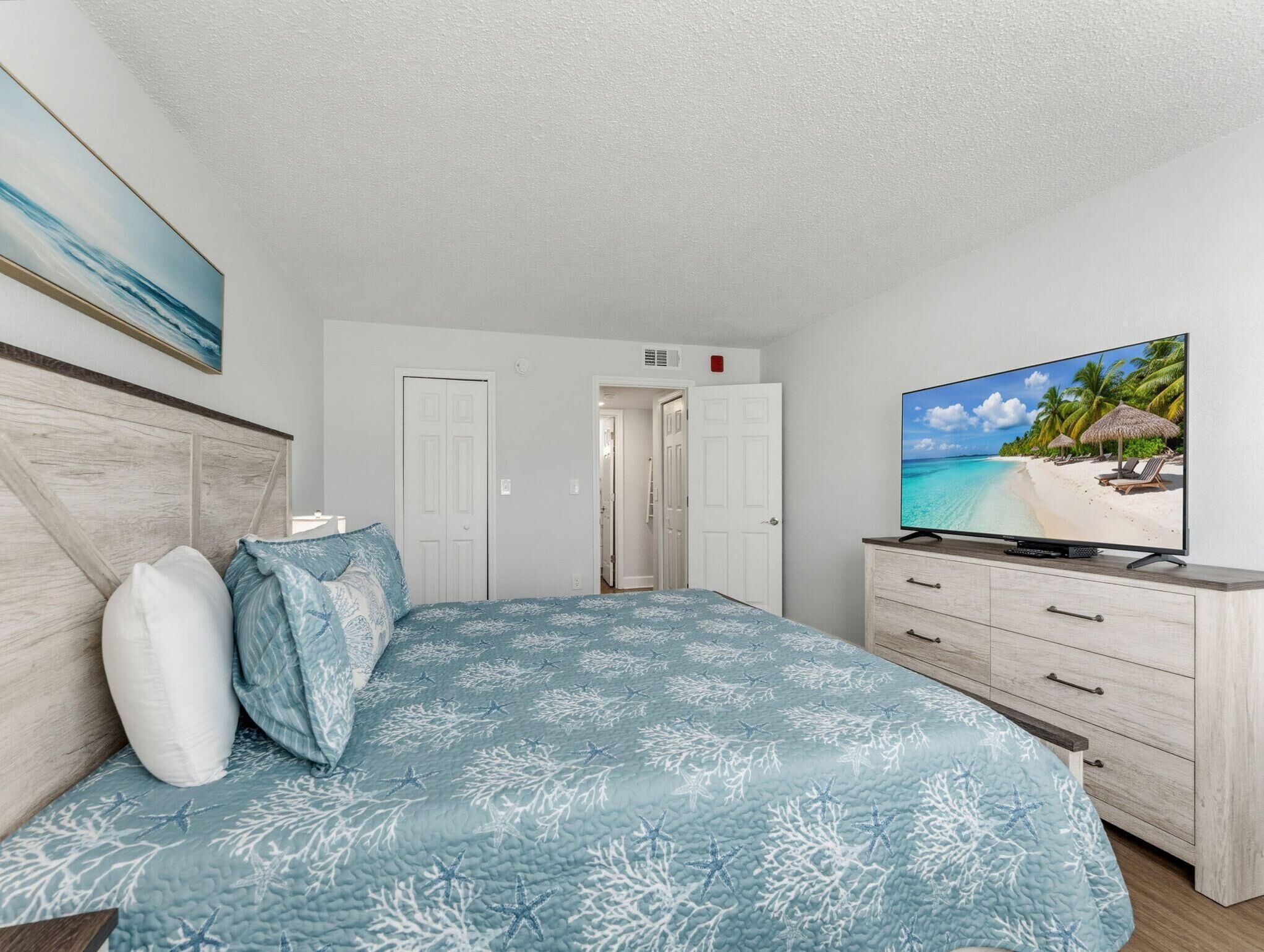 A bedroom with a bed, a television, and a door leading to another room.