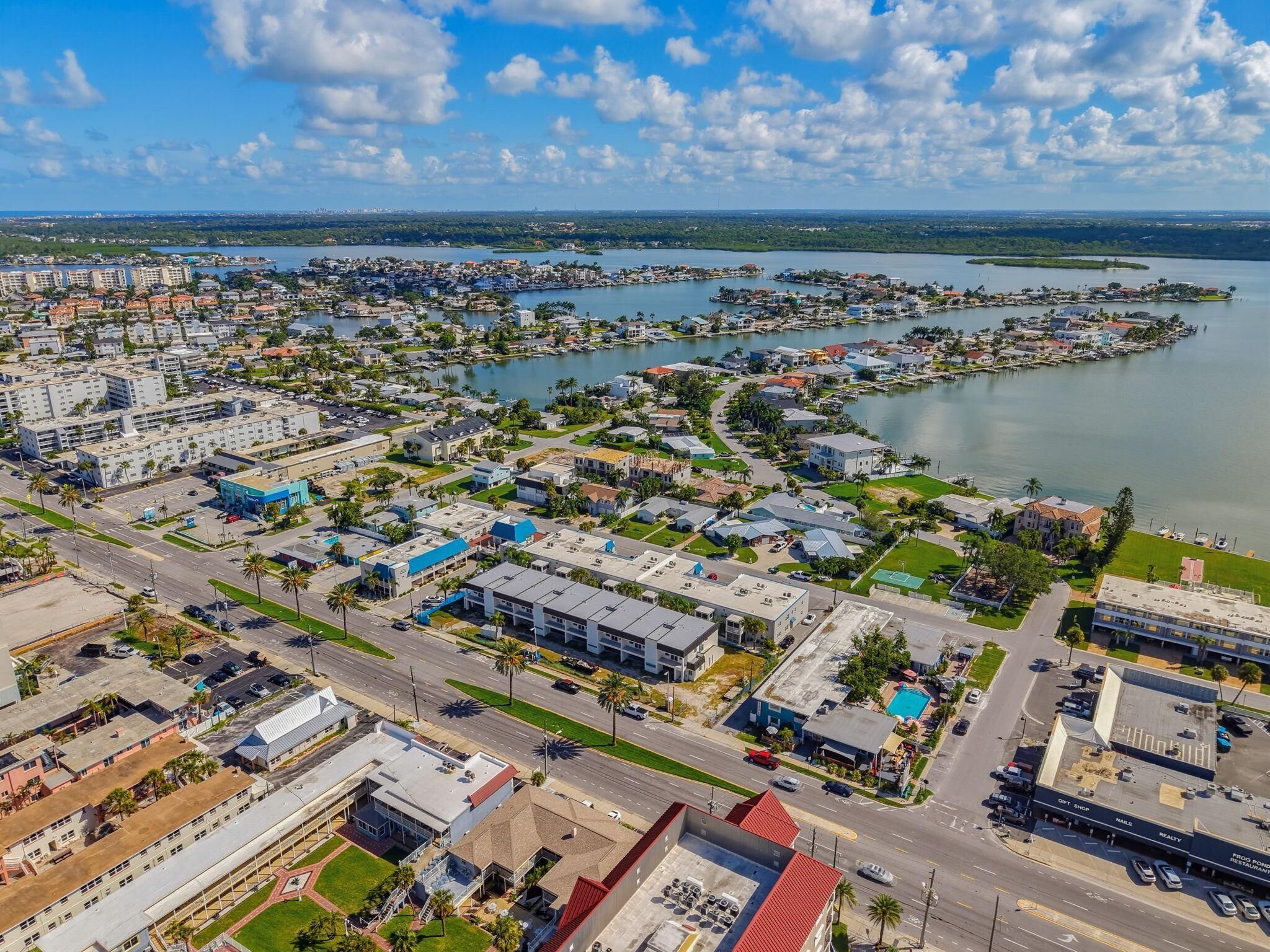 An aerial view of a coastal residential area with multiple buildings, roads, and a marina.
