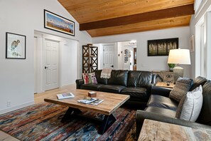 Ein Wohnzimmer mit einer schwarzen Ledersofa, einem Holztisch und einem farbenfrohen Teppich.