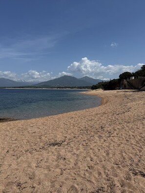 A beach with clear water, a sandy shore, and mountains in the background. - Right on the Water: Stunning Apartment in Porticcio (Grosseto-Prugna)