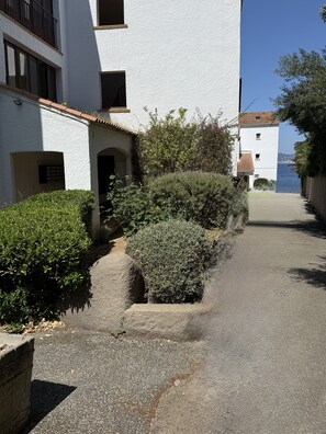 A narrow street flanked by white buildings with balconies, leading to a body of water. - Right on the Water: Stunning Apartment in Porticcio (Grosseto-Prugna)