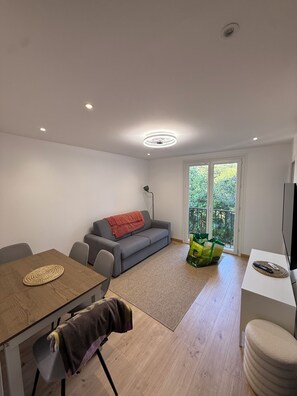A modern living room with a sofa, a dining table, and a TV. - Right on the Water: Stunning Apartment in Porticcio (Grosseto-Prugna)