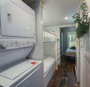 A laundry area with a washing machine and dryer, a bunk bed, and a small seating area with a plant. - Everly House | Waterfall + Private Trails (Monteagle)