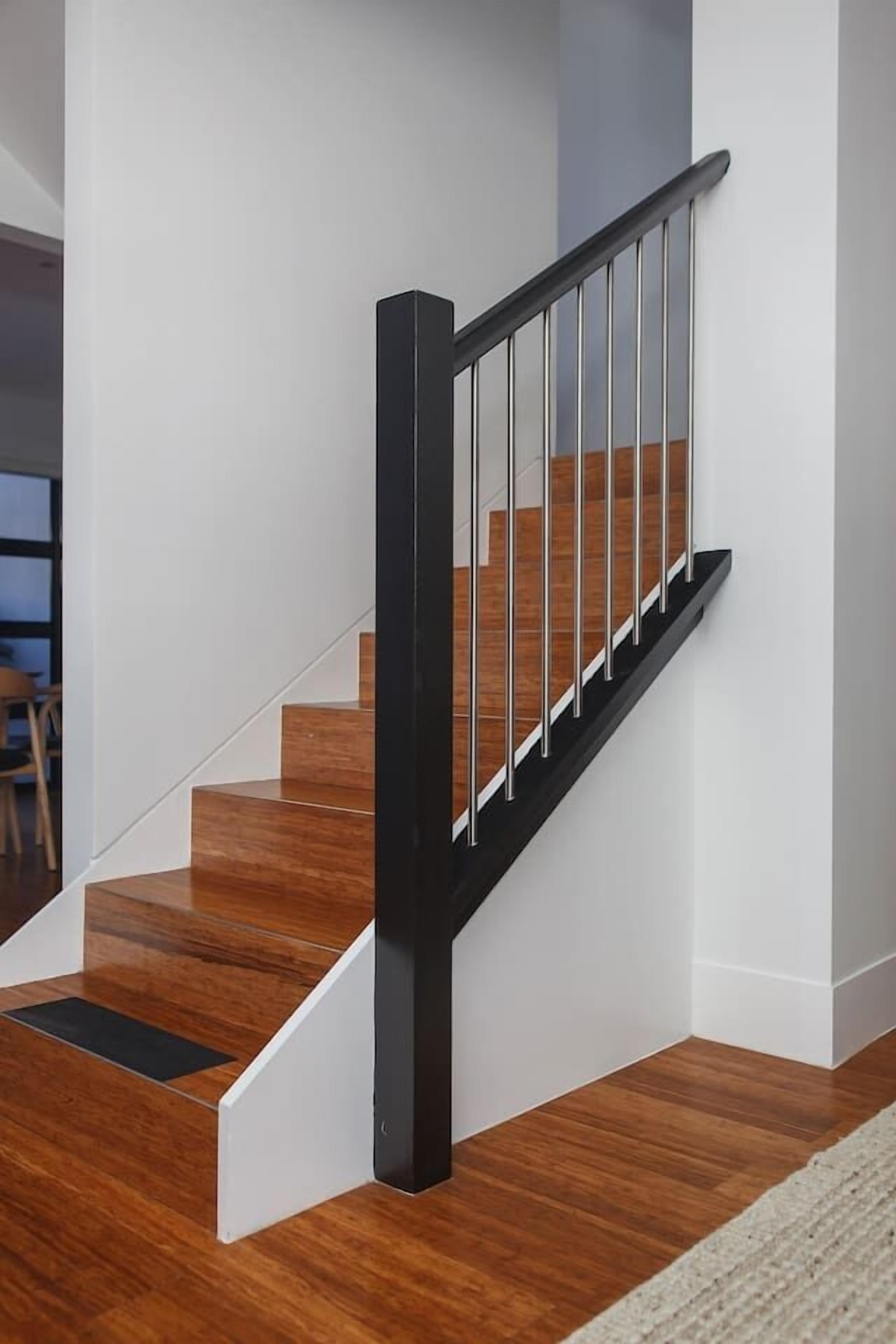 Eine Treppe mit Holzbodenstufen und einem schwarzen Geländer.
