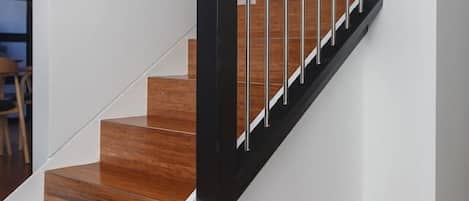 A staircase with wooden steps and a black handrail.
