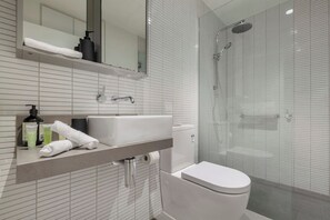 Un baño moderno con inodoro, lavamanos y ducha.