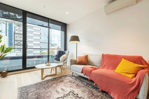 Ein modernes Wohnzimmer mit großem Fenster, einer Couch, einem Couchtisch und einer Stehlampe.