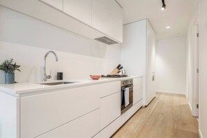 Eine moderne Küche mit weißer Arbeitsplatte, Edelstahlgeräten und Holzboden.