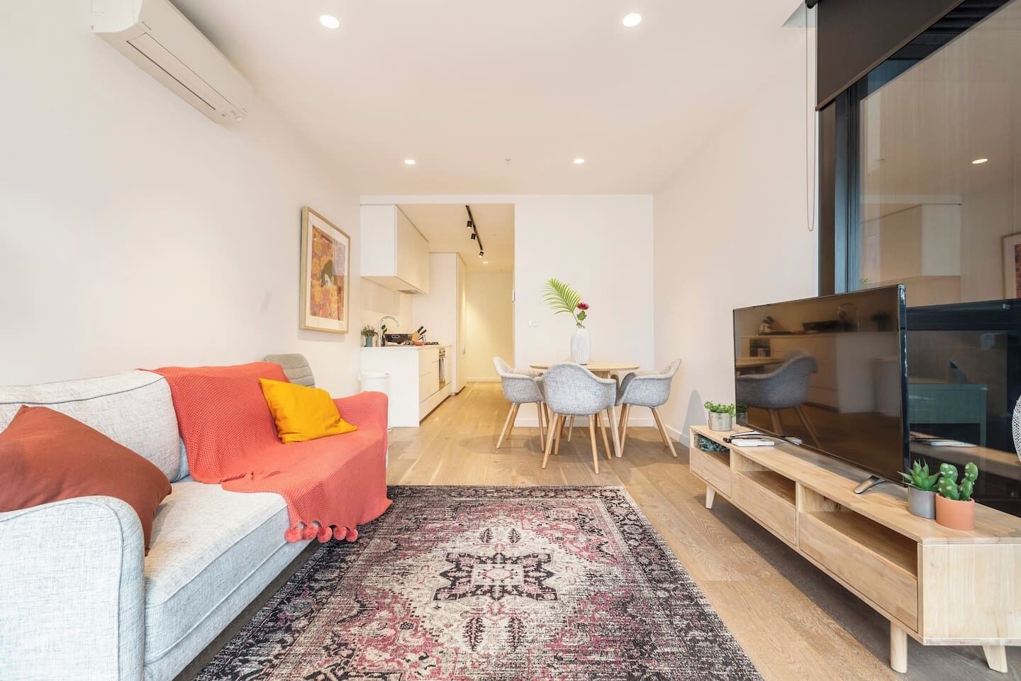 Un salon moderne avec un canapé, une table basse et un téléviseur. Il y a également un coin repas avec des chaises et une table.