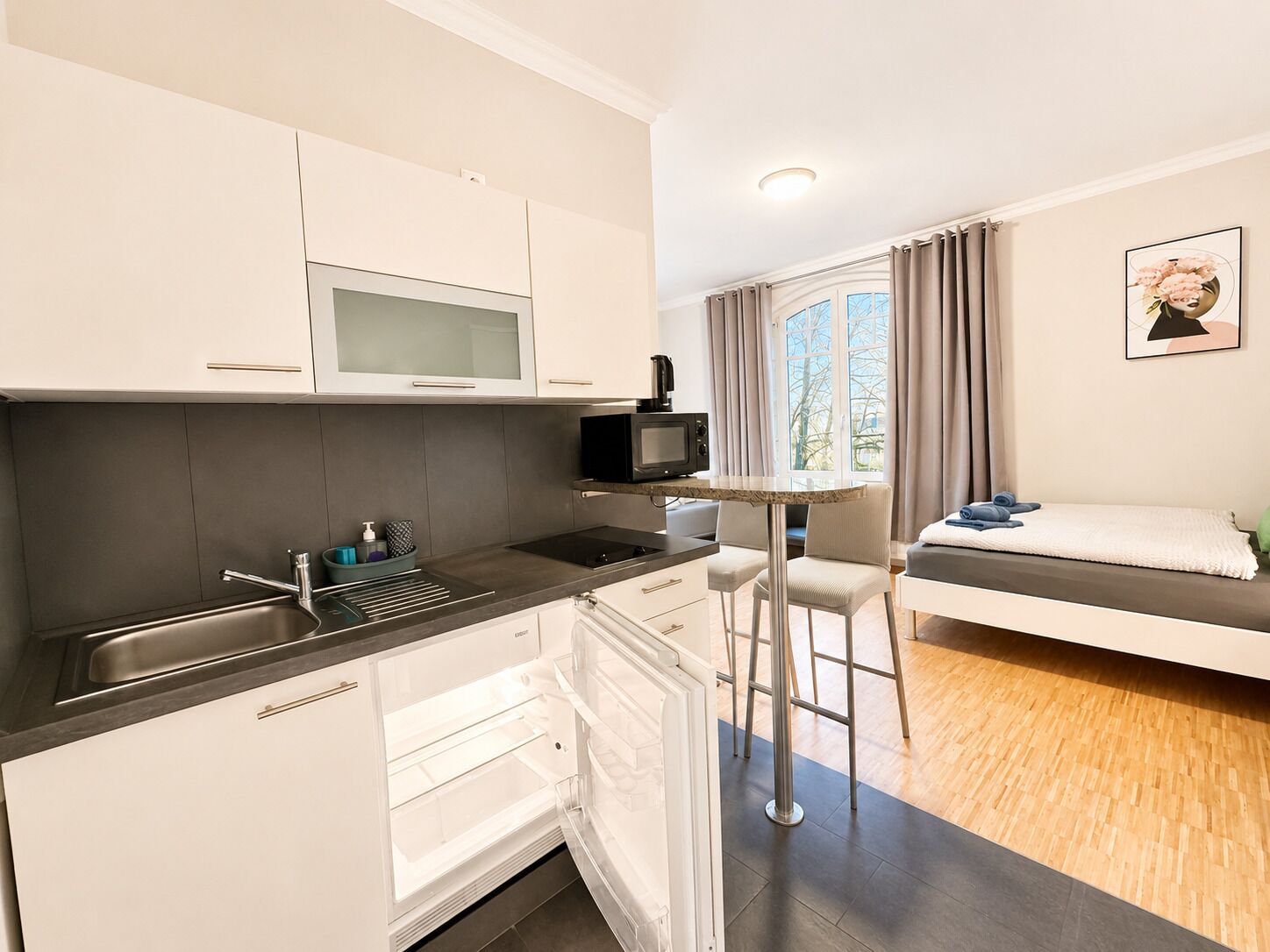 A compact kitchen with a microwave, a sink, and a small dining area with a table and chairs.
