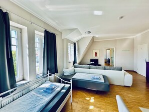 A modern bedroom with a bed, a sofa, a television, and a window with curtains. - Apartmenthouse Singen  (Singen (Hohentwiel))