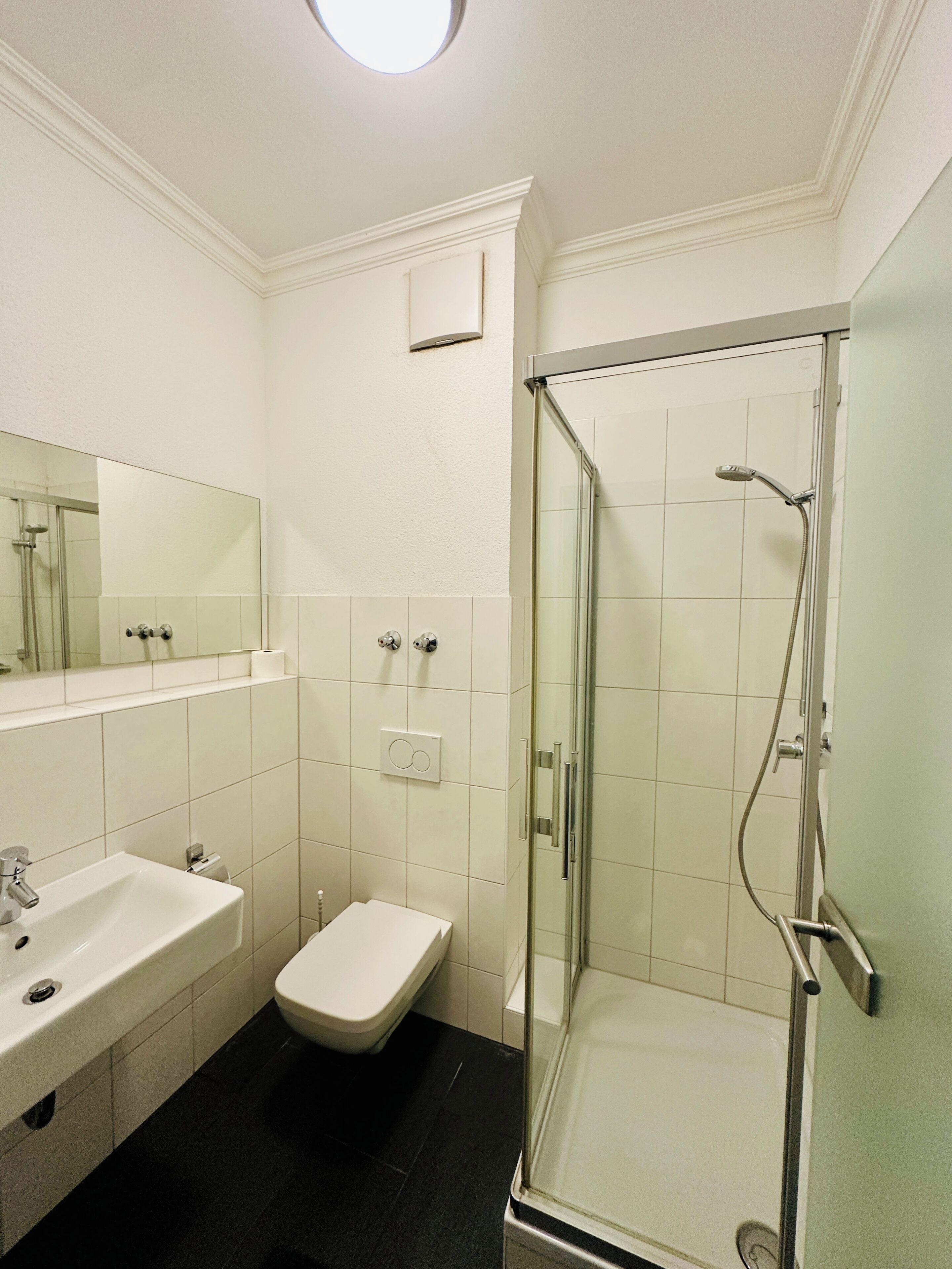 A bathroom with a glass-enclosed shower, a white sink, and a toilet.