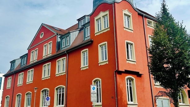 Um edifício vermelho com várias janelas e uma girafa no topo.