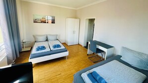 A hotel room with a bed, a desk, a chair, and a wardrobe.