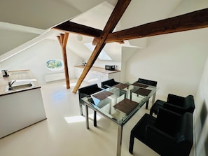 A modern kitchen with a glass dining table, black chairs, and a view of the outdoors. - Apartmenthouse Singen  (Singen (Hohentwiel))
