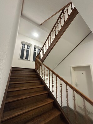 A wooden staircase with a glass balustrade leading to a landing. - Apartmenthouse Singen (Singen (Hohentwiel))