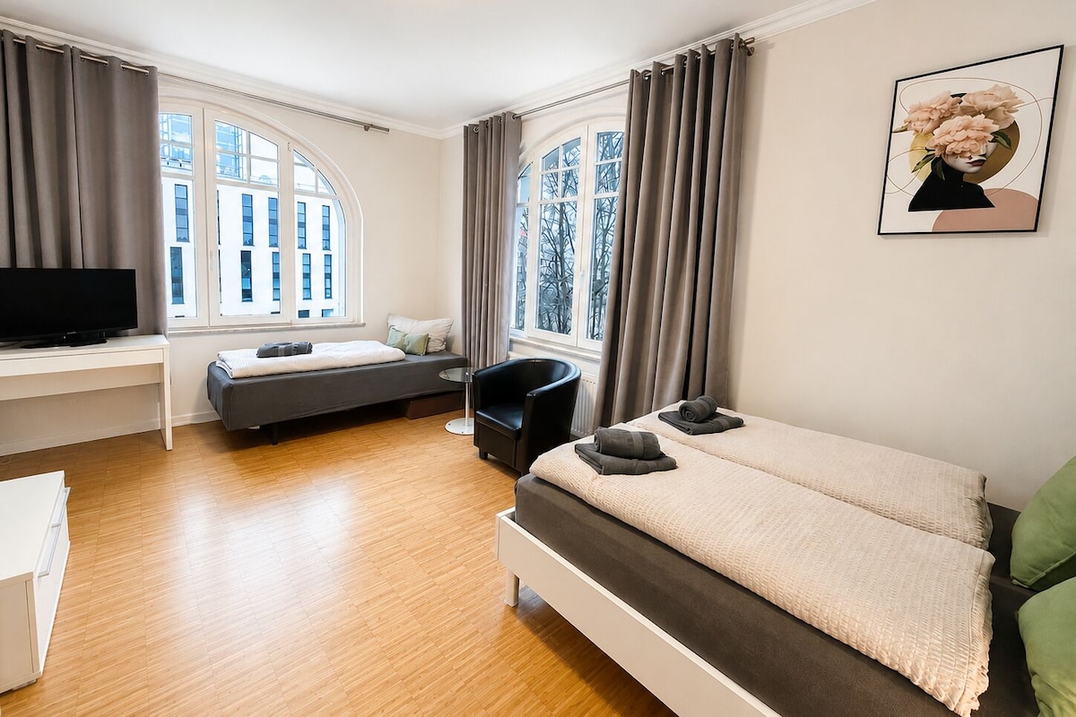 A modern bedroom with a bed, a desk, a chair, and a television.