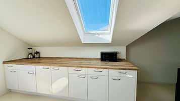 Eine Küche mit Oberlicht, weißen Schränken und einer Holzausziehtafel.