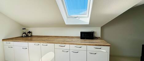 A kitchen with a skylight, white cabinets, and a wooden countertop.