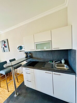 A compact kitchen with a microwave, sink, and modern cabinetry.