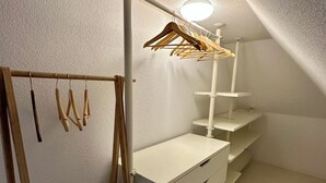 A room with a white wardrobe, a wooden coat rack, and a ceiling light fixture.