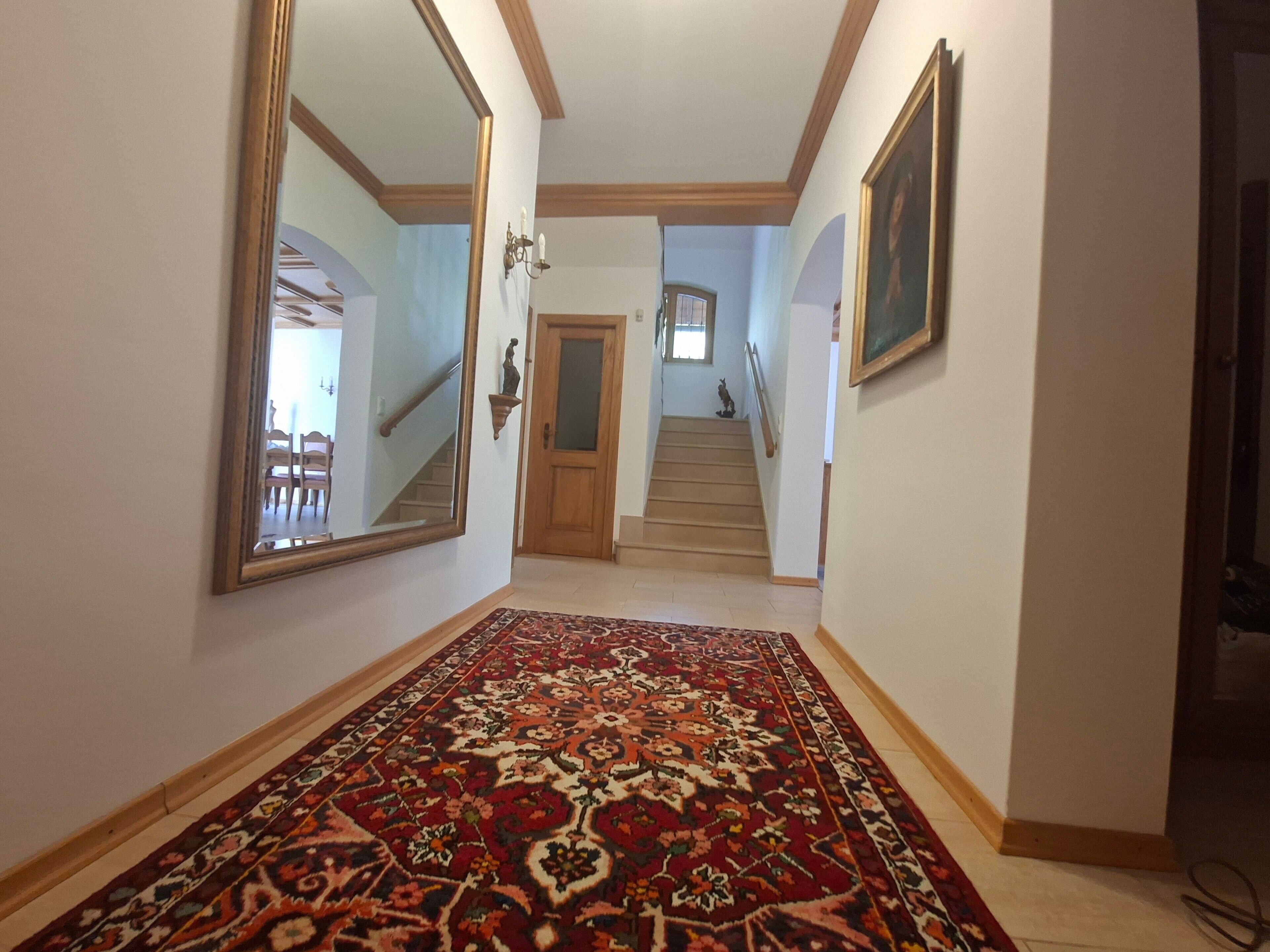 A hallway with a patterned carpet, a wooden door, and a staircase leading to another level.