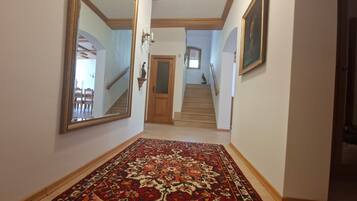 A hallway with a patterned carpet, a wooden door, and a staircase leading to another level.