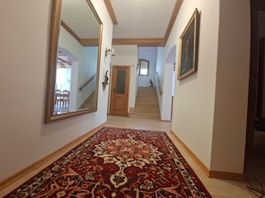 A hallway with a patterned carpet, a wooden door, and a staircase leading to another level.