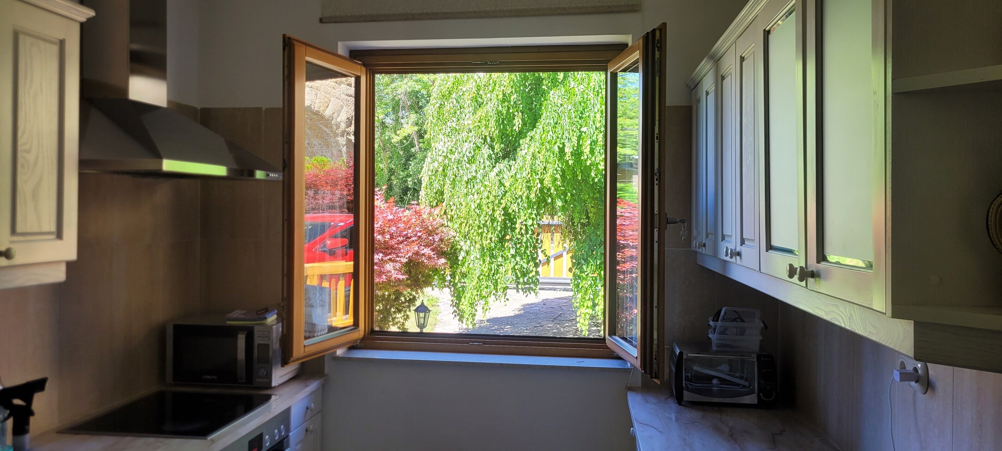 A kitchen with a view of a garden through an open door.