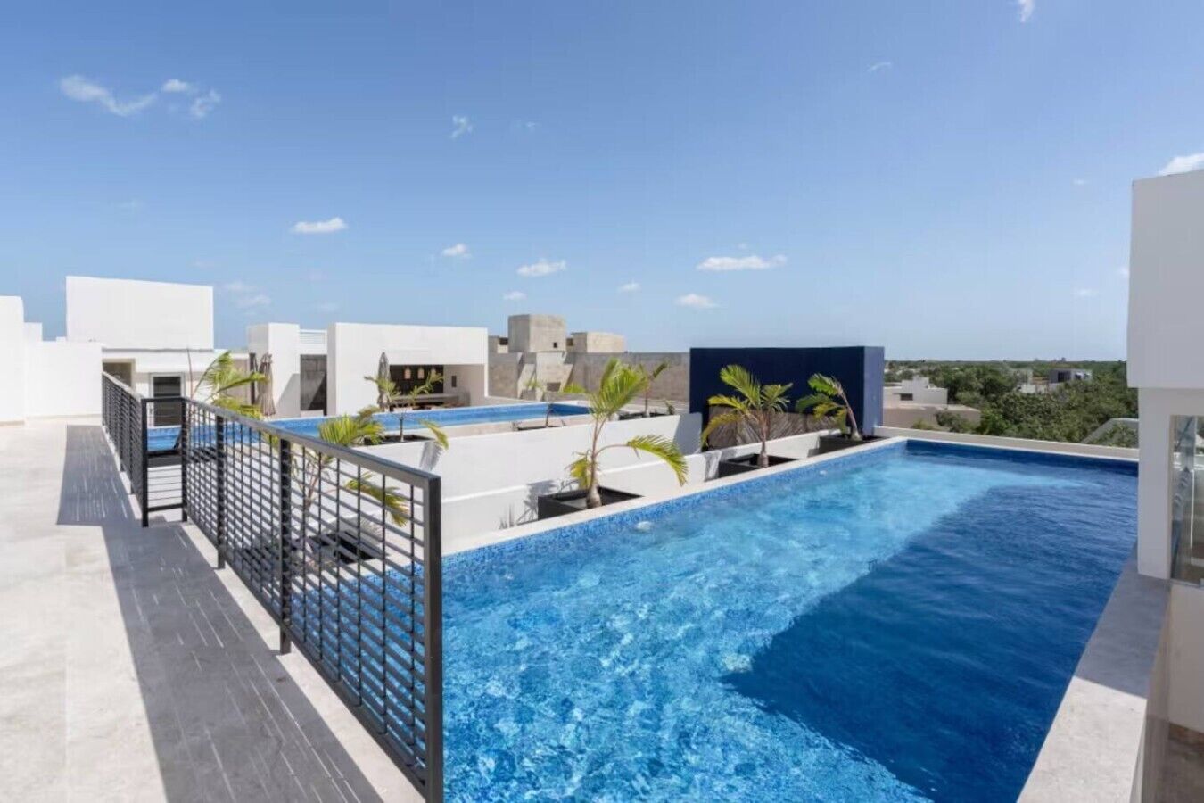 A rooftop swimming pool with a clear view of the sky and surrounding buildings.