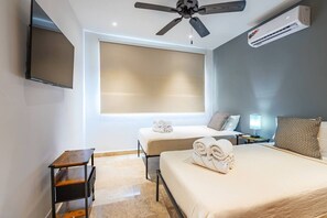 A hotel room with a bed, a desk, a ceiling fan, an air conditioner, and a window with blinds. - Luxury 2BR | Private Plunge Pool | Rooftop & Gym (Tulum)