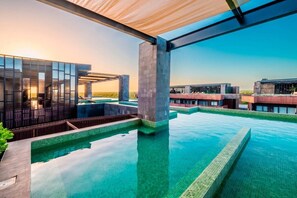 Une piscine à débordement située sur le toit, avec une eau d’un bleu cristallin, entourée d’une architecture moderne et offrant une vue sur l’horizon.