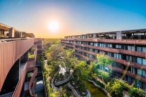 A modern building complex with multiple floors, a central courtyard with a water feature, and a clear sky. - Peaceful 1BR Near Beach | Rooftop Pool | Sleeps 4 (Tulum)