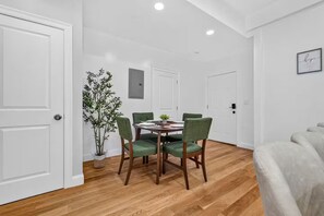 Un coin repas comprenant une table ronde, quatre chaises, une plante en pot et un luminaire fixé au mur.