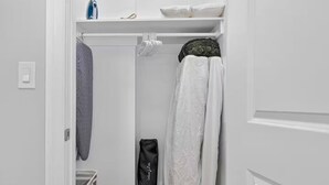 Un vestidor amplio con espacio para colgar, una toalla doblada y un bolso negro.