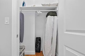 Un dressing avec espace pour suspendre des vêtements, une serviette pliée et un sac noir.