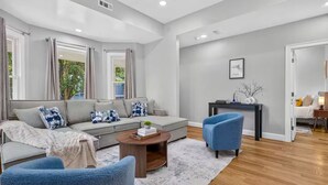 Una sala de estar moderna con un sofá gris, sillones azules, una mesa de centro y una mesita auxiliar con adornos.
