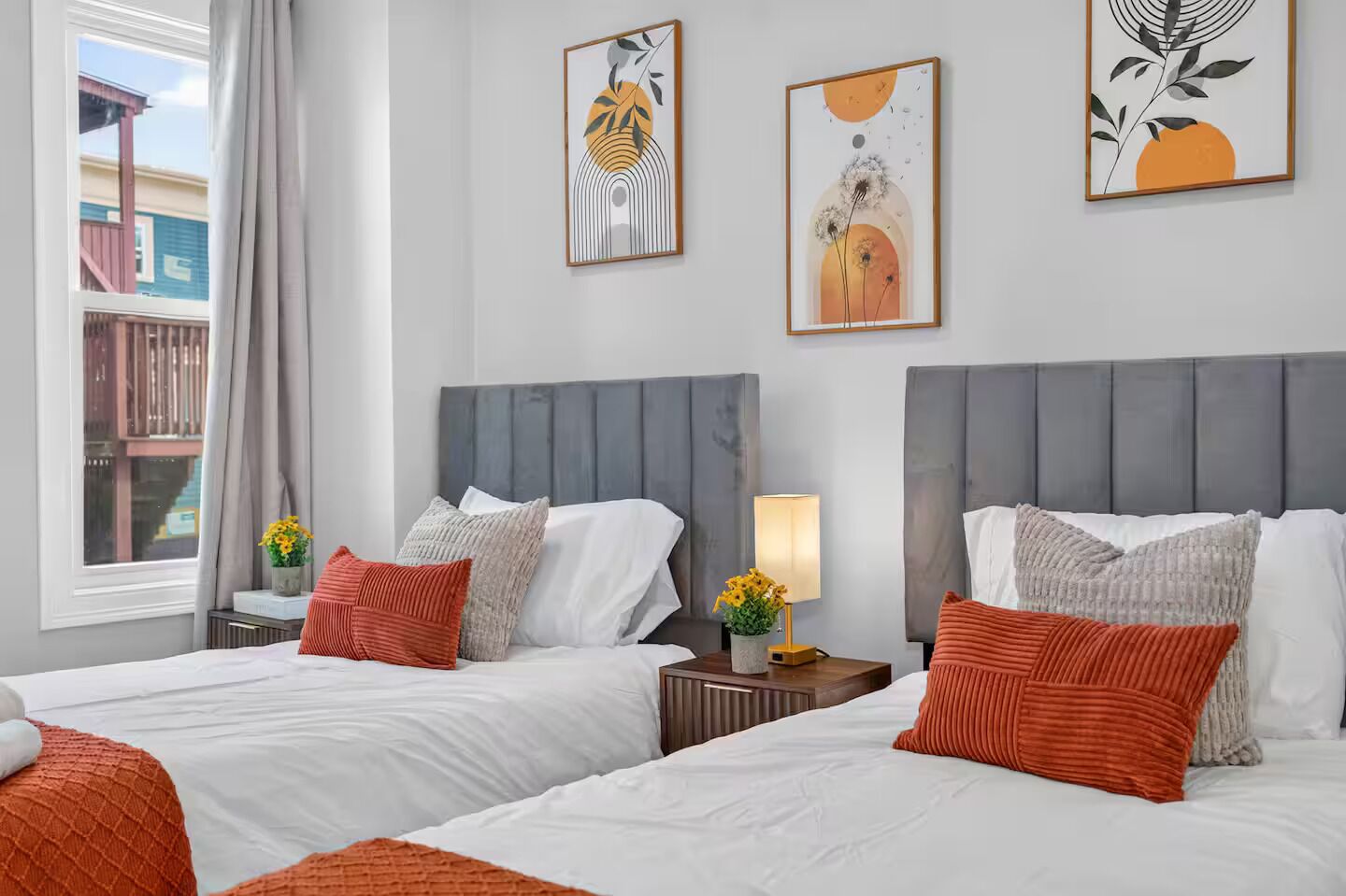 Habitació d'hotel amb dos llits, una finestra amb cortines i obres d'art a les parets.