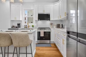 A modern kitchen with white cabinets, stainless steel appliances, and a central island with bar stools.