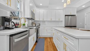 Una cocina moderna con armarios blancos, electrodomésticos de acero inoxidable y encimera gris.