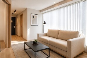 Ein Wohnzimmer mit einem beigefarbenen Sofa, einem schwarzen Couchtisch und einem gerahmten Kunstwerk an der Wand.