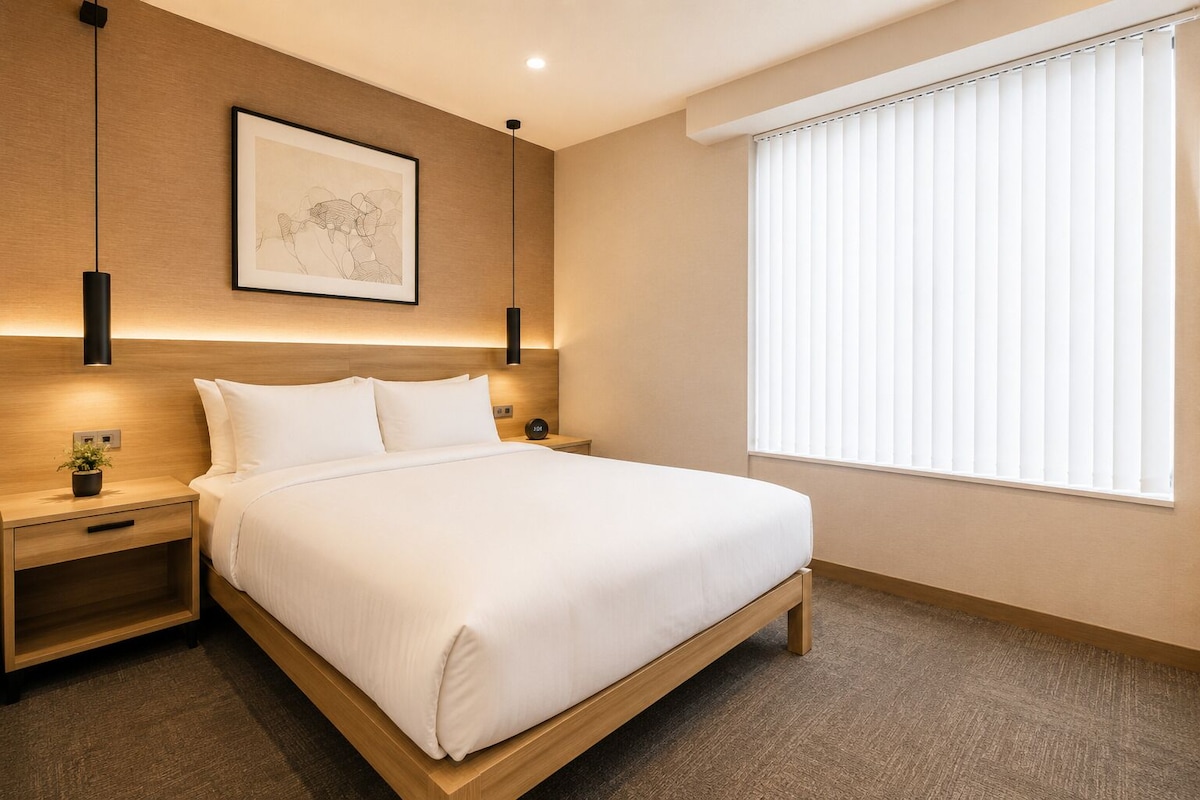 Ein Hotelzimmer mit einem Bett, Nachttischen, einem Wandbild, einem Fenster mit Jalousien und einem Teppichboden.