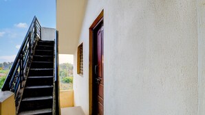 Escales que condueixen a una porta amb una finestra, una paret blanca i un cel serè.
